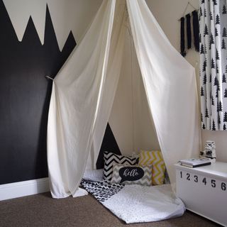 children room with calico fabric tent and white toy box