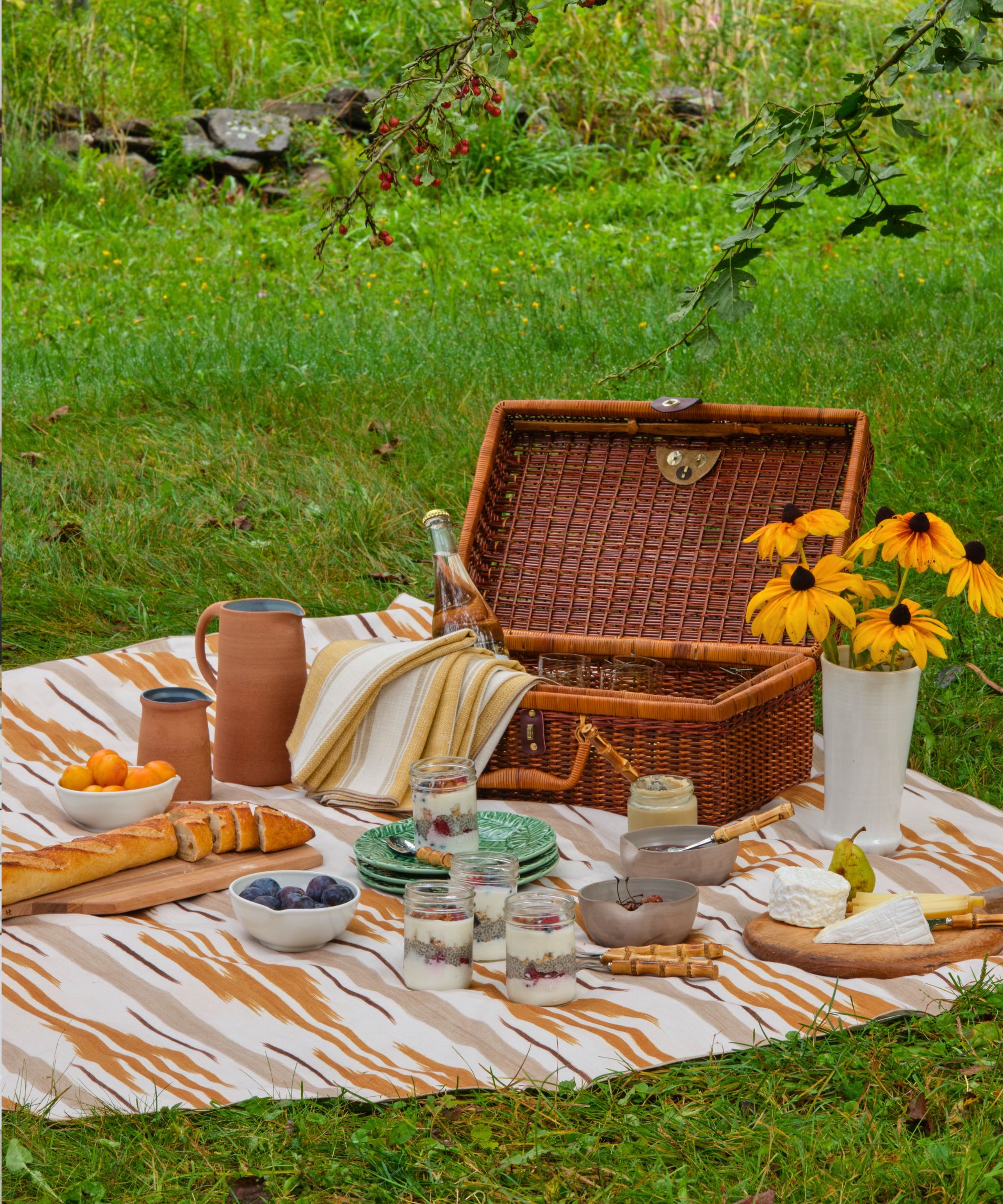Picnic on the lawn with a classic wicker picnic basket and a blanket and napkins made from Brunschwig & Fils fabric