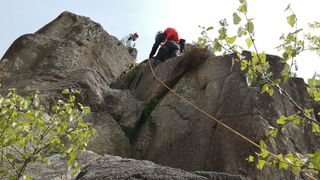 people scrambling with ropes over rocky terrain