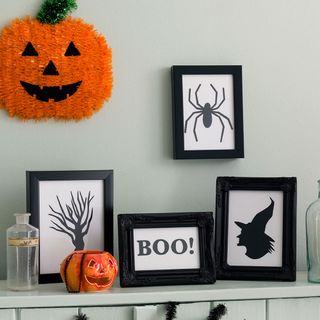 Black halloween pictures on wall with pumpkins