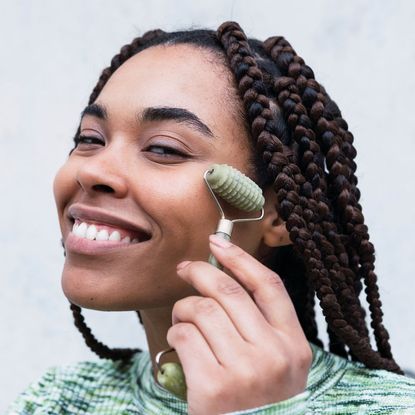 a woman using a face roller - facial massage