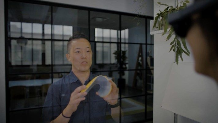 A person with an AR headset viewing a hologram presentation