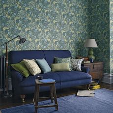 living area with wallpaper wall with blue sofa and wooden floor and rug