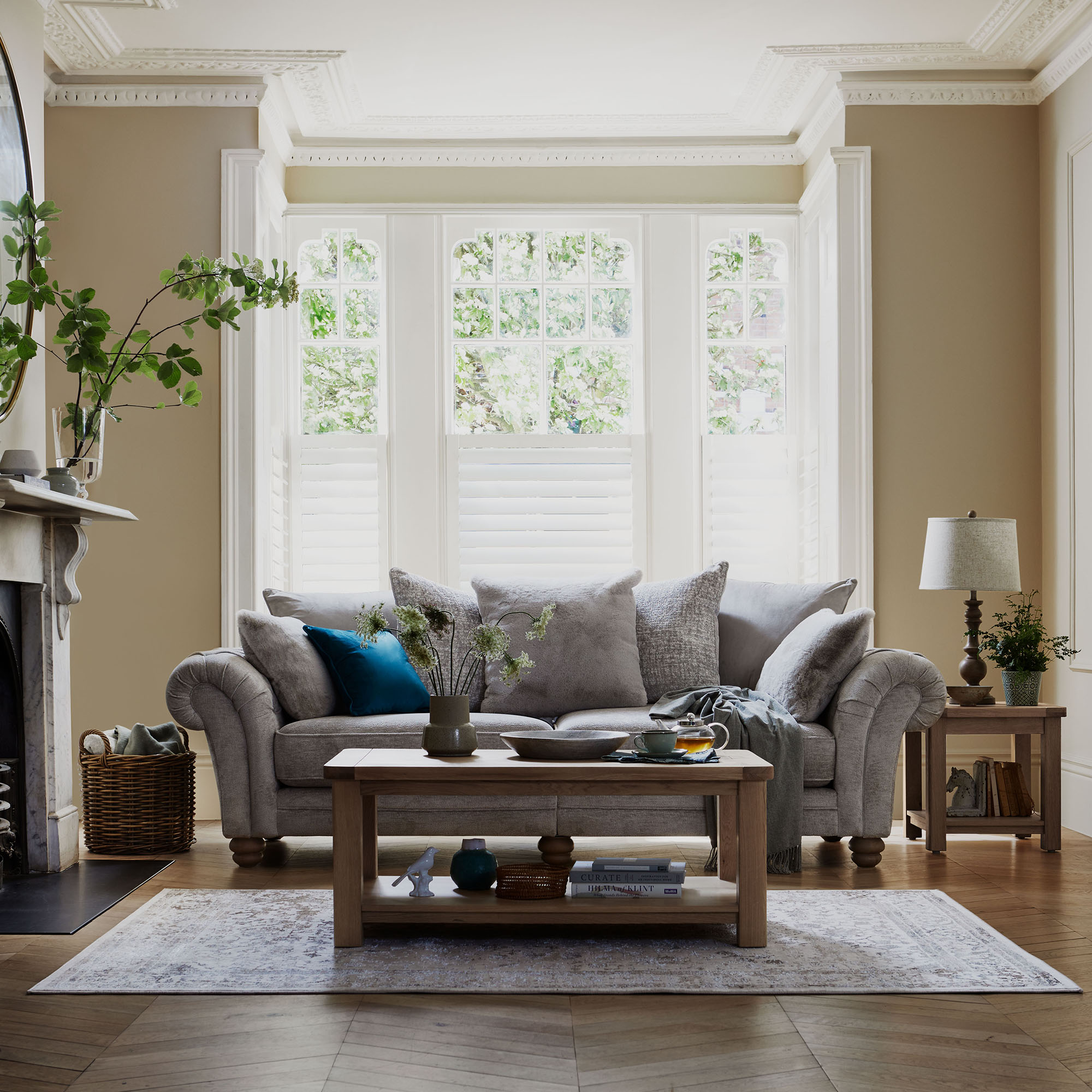 Cream traditional sofa with scrolled arms and layered cushions in a period style living room with wooden coffee table