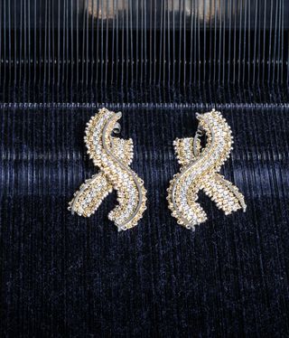 Megan Brown's gold threaded earrings on a black background