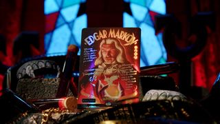 Edgar Markov foil special card standing on a surface amongst vampire fans, chains, and blood vials in front of a stained glass windows