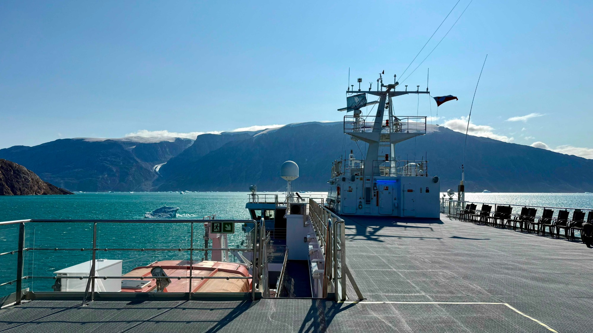 the deck of a ship surrounded by icy blue waters and mountain peaks