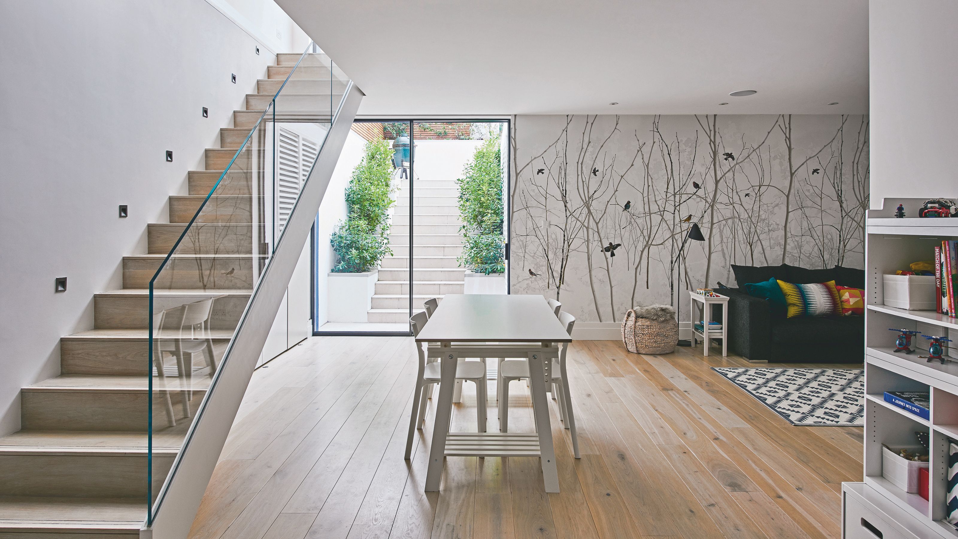 Converted basement with sliding glass doors to bring in light, dining table and cosy sofa