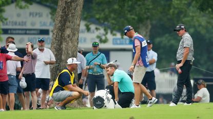 Aaron Wise holds his head after being struck by a golf ball
