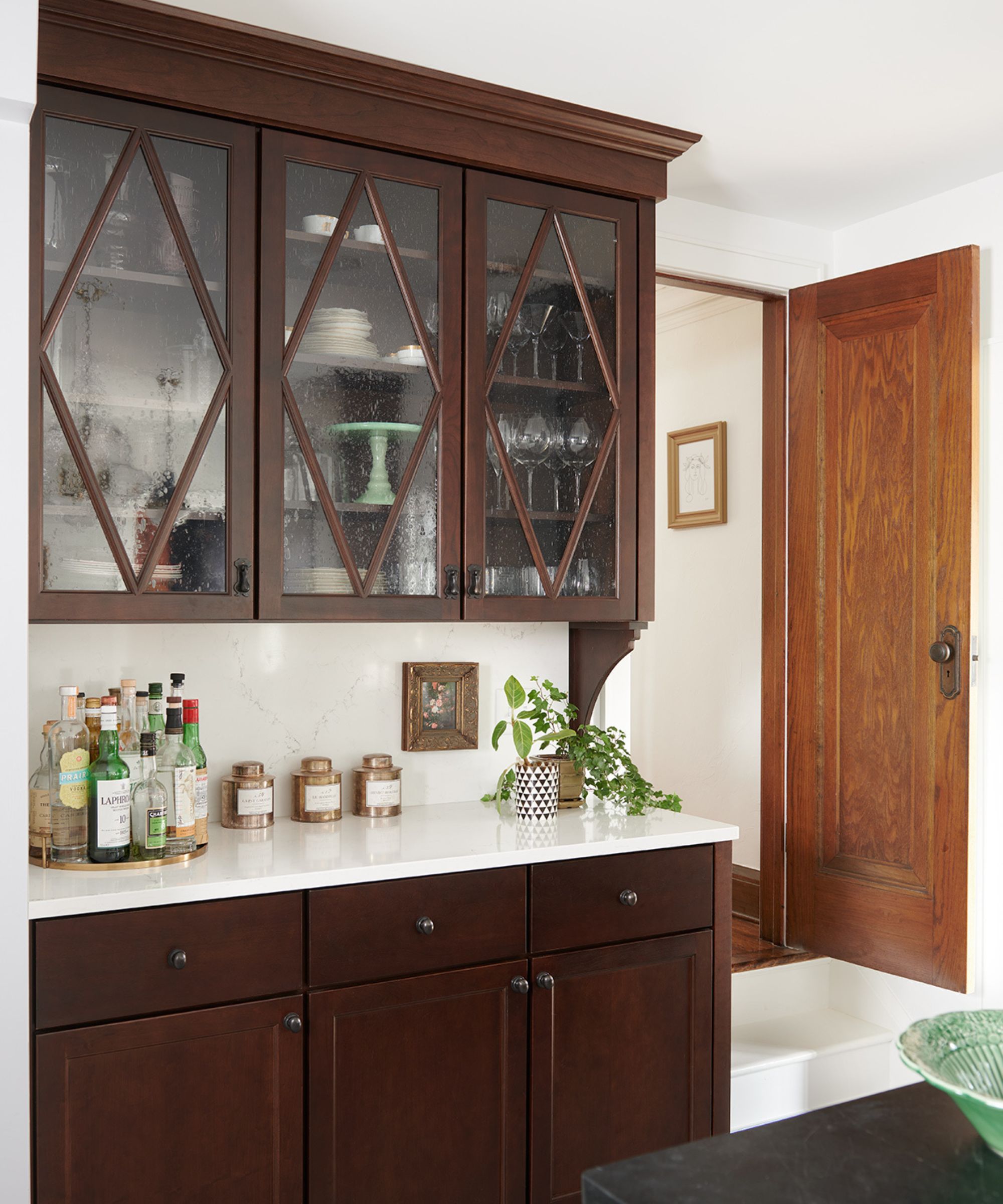 A kitchen corner with dark wooden cabinets and glazed upper cabinetry