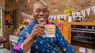 Ainsley Harriott celebrating the coronation with a special cookery show, holding a coronation mug