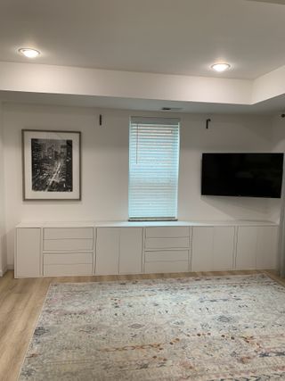 A living room with plain white IKEA eket cabinets lining the wall under the window