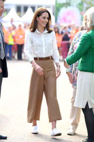 Kate Middleton trug weiße Superga-Sneaker mit einer weißen Bluse und einer braunen Hose