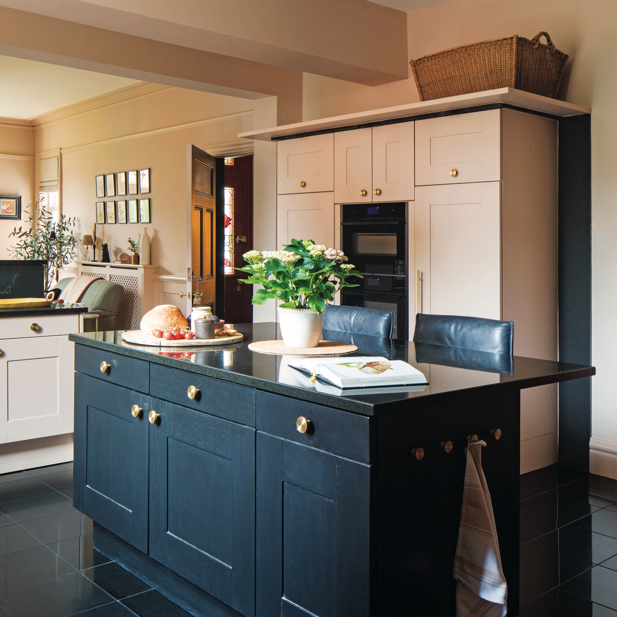 kitchen with large black island with seating, and cabinetry and walls in plaster pink
