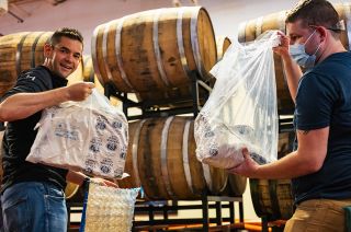 Inspiration4 commander Jared Isaacman (left) unpacks the flown hops used in Space Craft at the Samuel Adams Brewery in Boston.