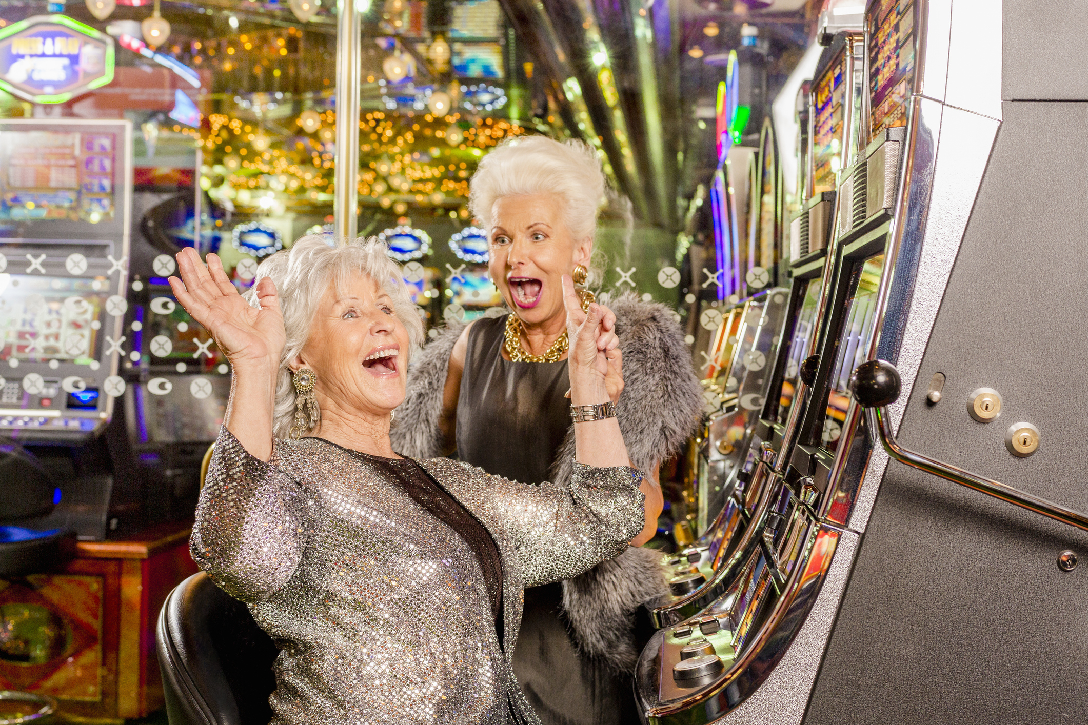 Two old ladies are happy playing the slot machine