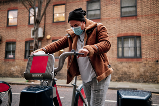 man getting onto Boris bike in London wearing face mask