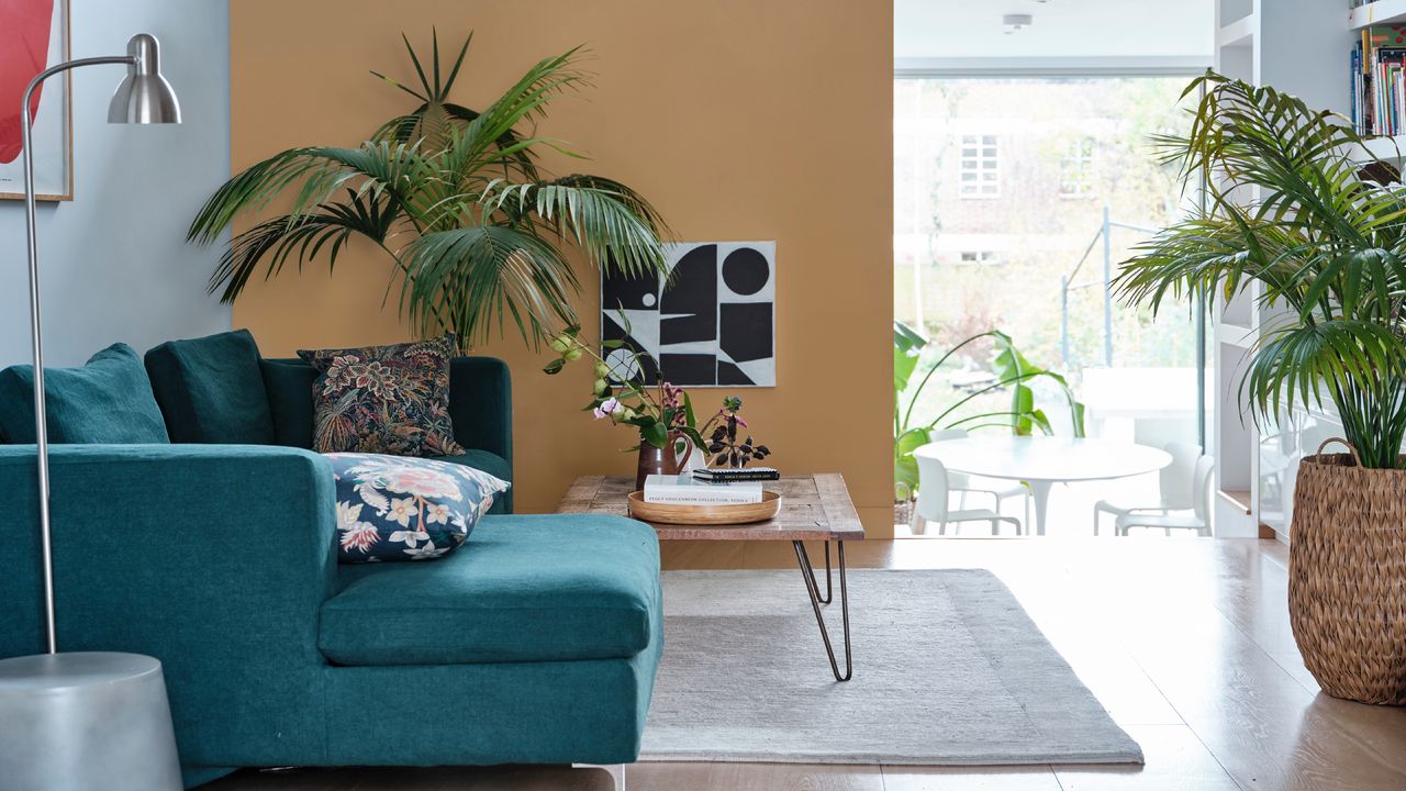 open-plan living room ideas, split level living room and dining space, teal sofa, coffee table, plants, ochre half wall