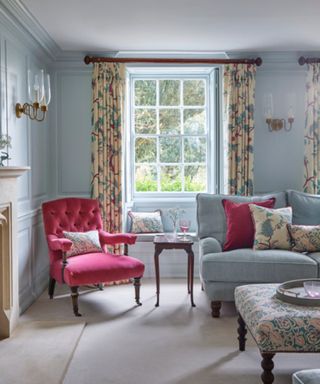 Blue living room with floral curtains and an antique armchair and traditional sofa