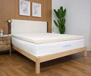 Turmerry Latex Mattress Topper against a wood wall.