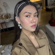 A woman taking a selfie with glowing skin wearing a wedding headpiece
