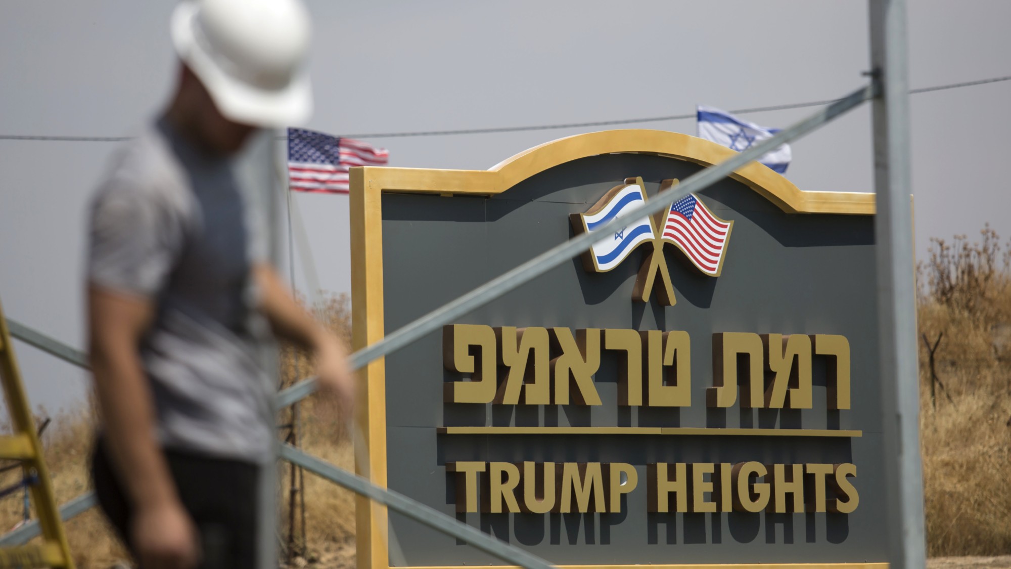 An Israeli man works near a sign for a new settlement named after US President Donald Trump 