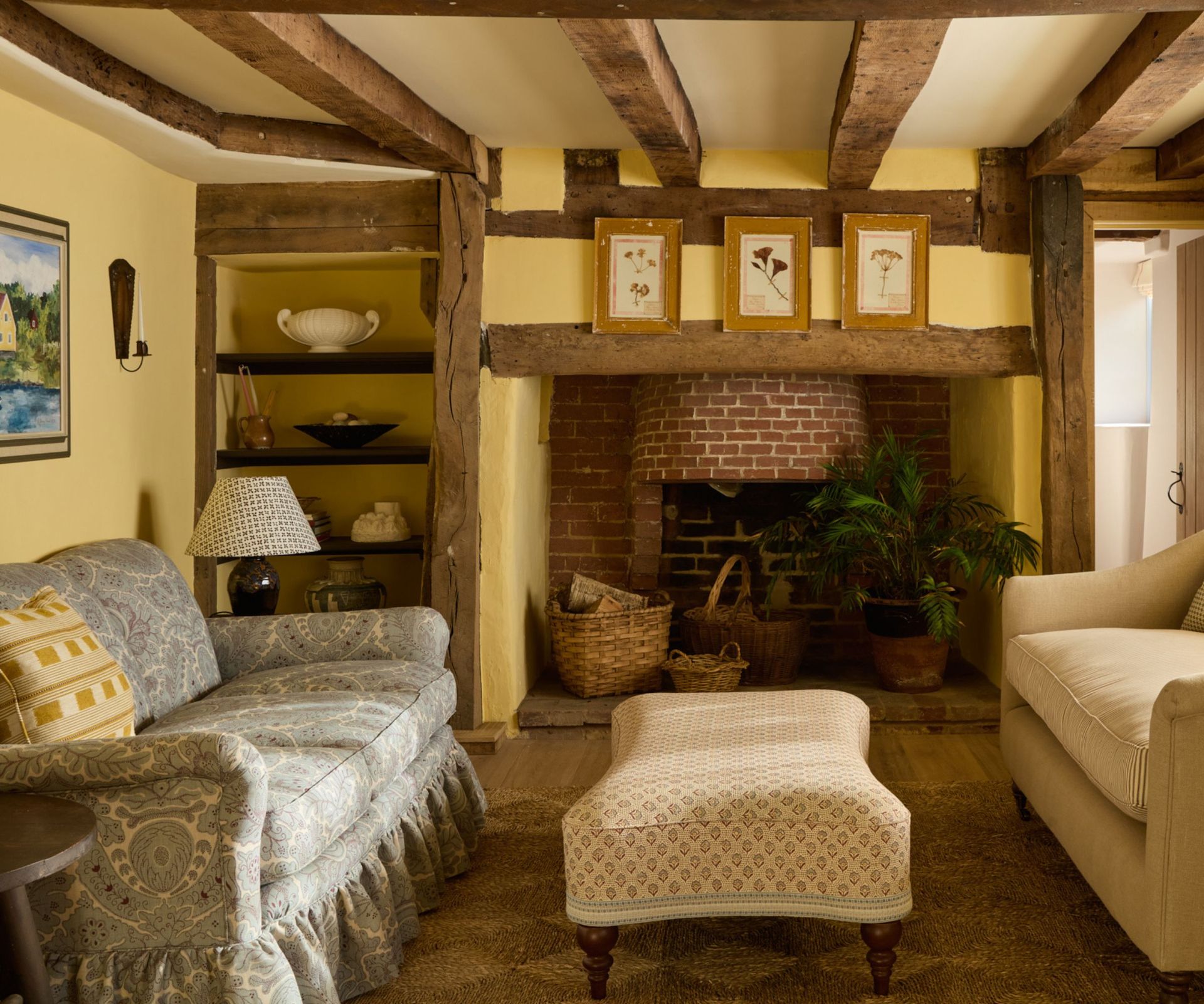 country style living room with beamed ceiling painted in a butter yellow with a blue patterned couch