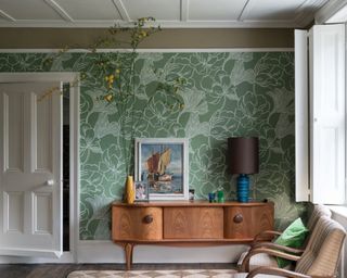 A traditional living room with green floral wallpaper wall decor and wooden sideboard