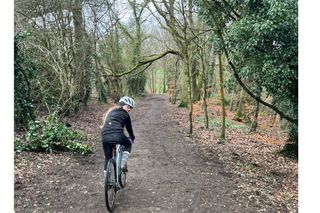 A child looking back riding a bike as she rides through the woods