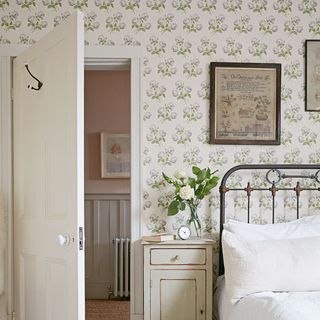 bedroom with white door and bed with cushions and wallpaper wall