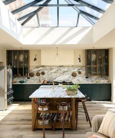 A blue and wood kitchen with a large kitchen island and marble countertops