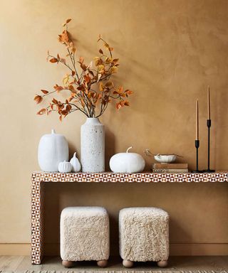 Orange wall, console table, fluffy stools, white pumpkins, candles