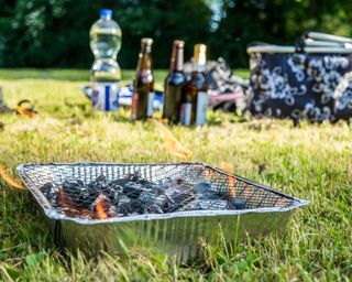 lit disposable BBQ on an area of grass