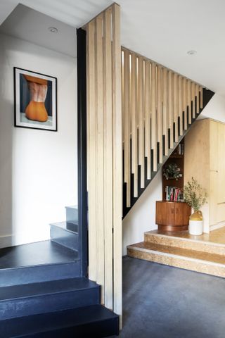 Staircase with black painted steps and full-height wooden slatted bannister
