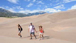 Family of three walking on dunes at Great Sand Dunes National Park