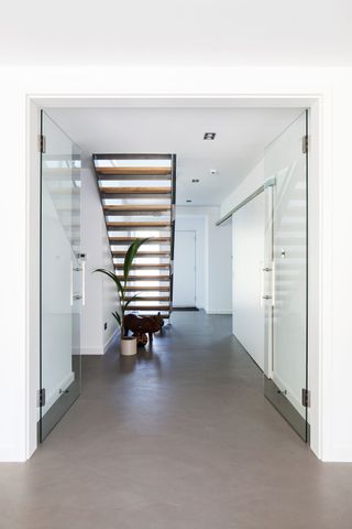 white minimalistic hallway with open staircase and grey flooring