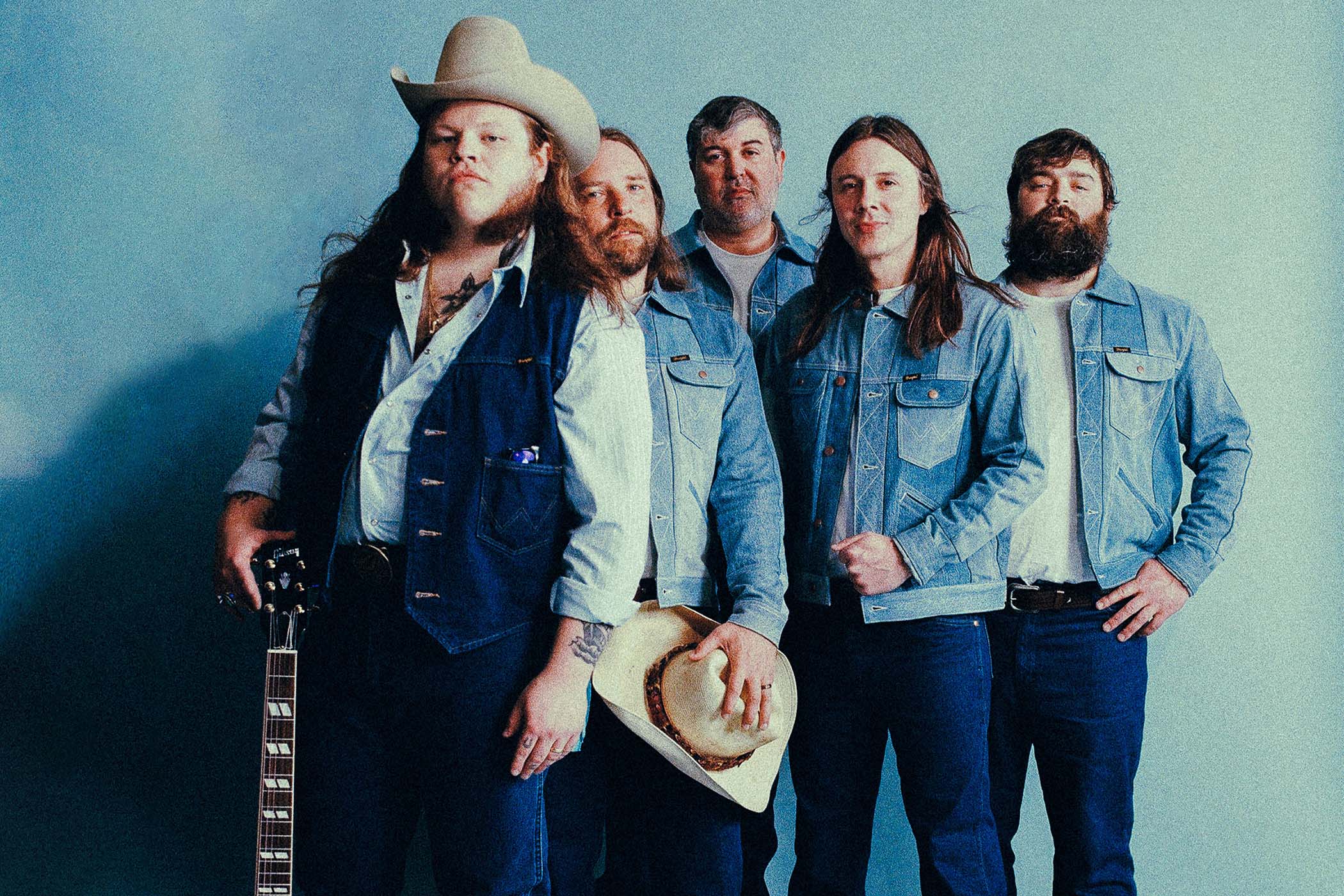 The Marcus King Band lined up in formation in double denim, with King at the far left with his Gibson ES-345 and cowboy hat