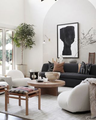 White living room with wood coffee table, white boucle armchairs and charcoal sofa