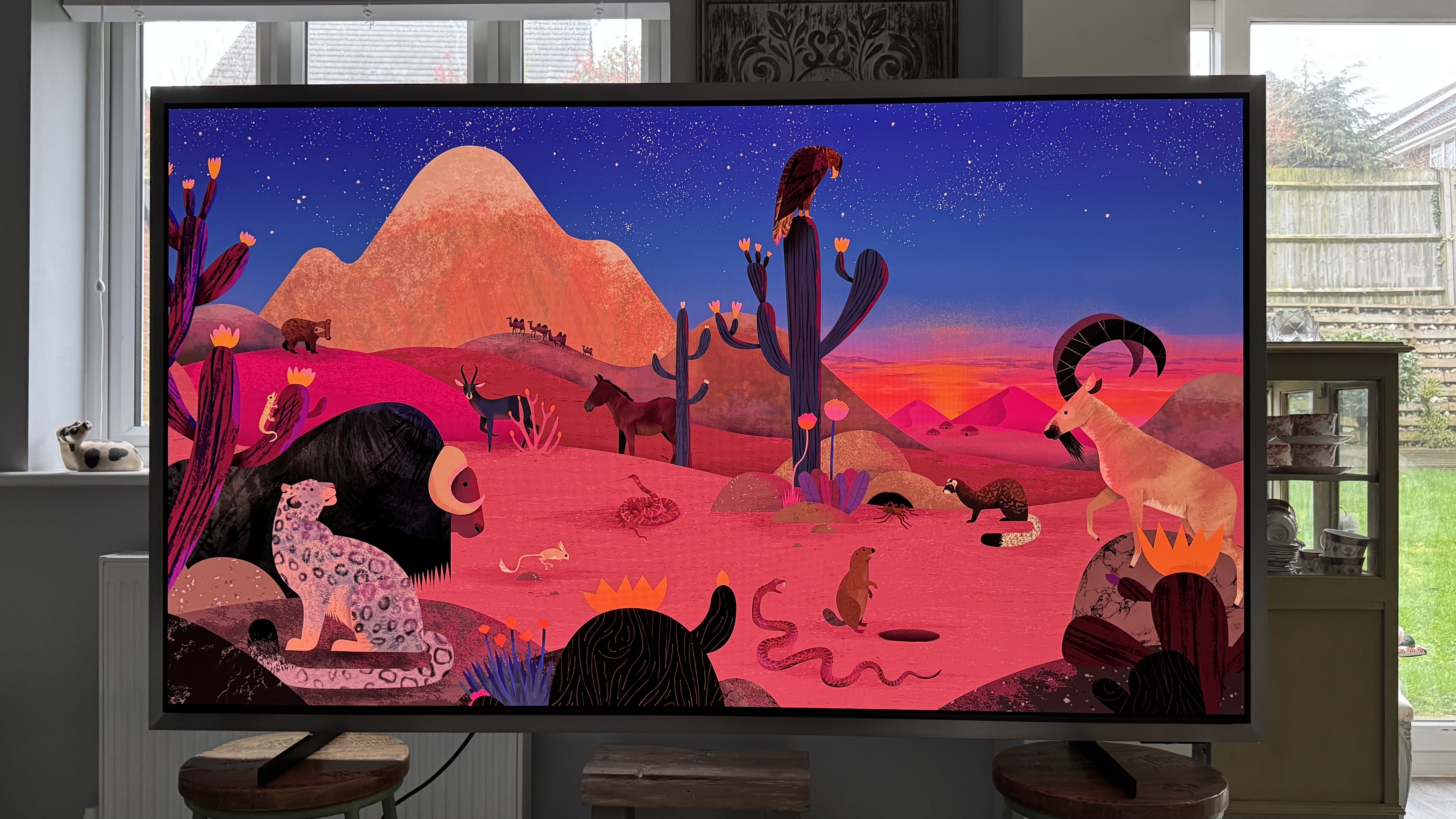 The Samsung S99H/S95H TV in a home, showing an abstract image of a desert scene on the screen, showing its punchy colours