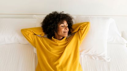 Smiling woman with her eyes closed lying on bed 