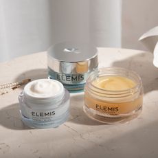 Three Elemis skincare products next to pearl necklace