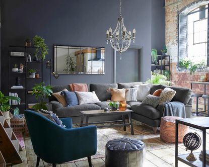 industrial boho style loft lounge living room with navy walls, blue sofa with textured cushions and accessories - dunelm