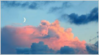 blue evening sky panorama with new moon and rose tinted clouds