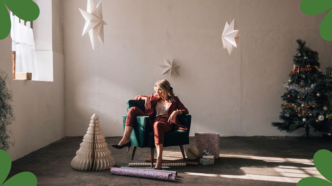 Woman surrounded by christmas wrapping paper wondering how to feel more festive