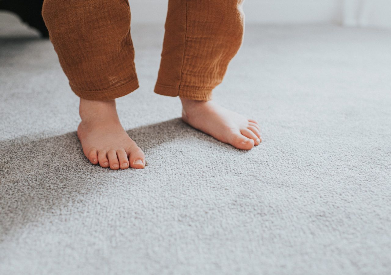 young child&#039;s feet on grey carpet