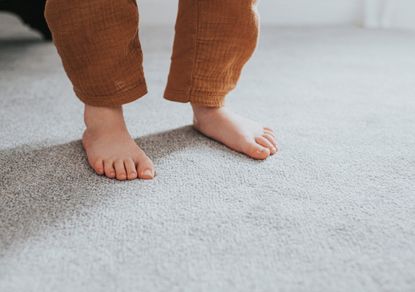 young child's feet on grey carpet