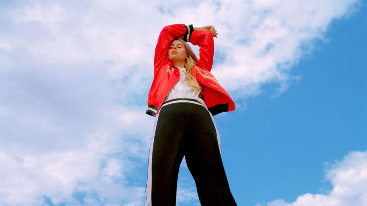 Young woman in fashionable clothing under a blue sky