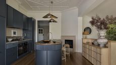 a traditional style kitchen with navy cabinetry and contemporary features