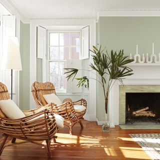 Living room with pale green walls, wooden flooring and rattan armchairs