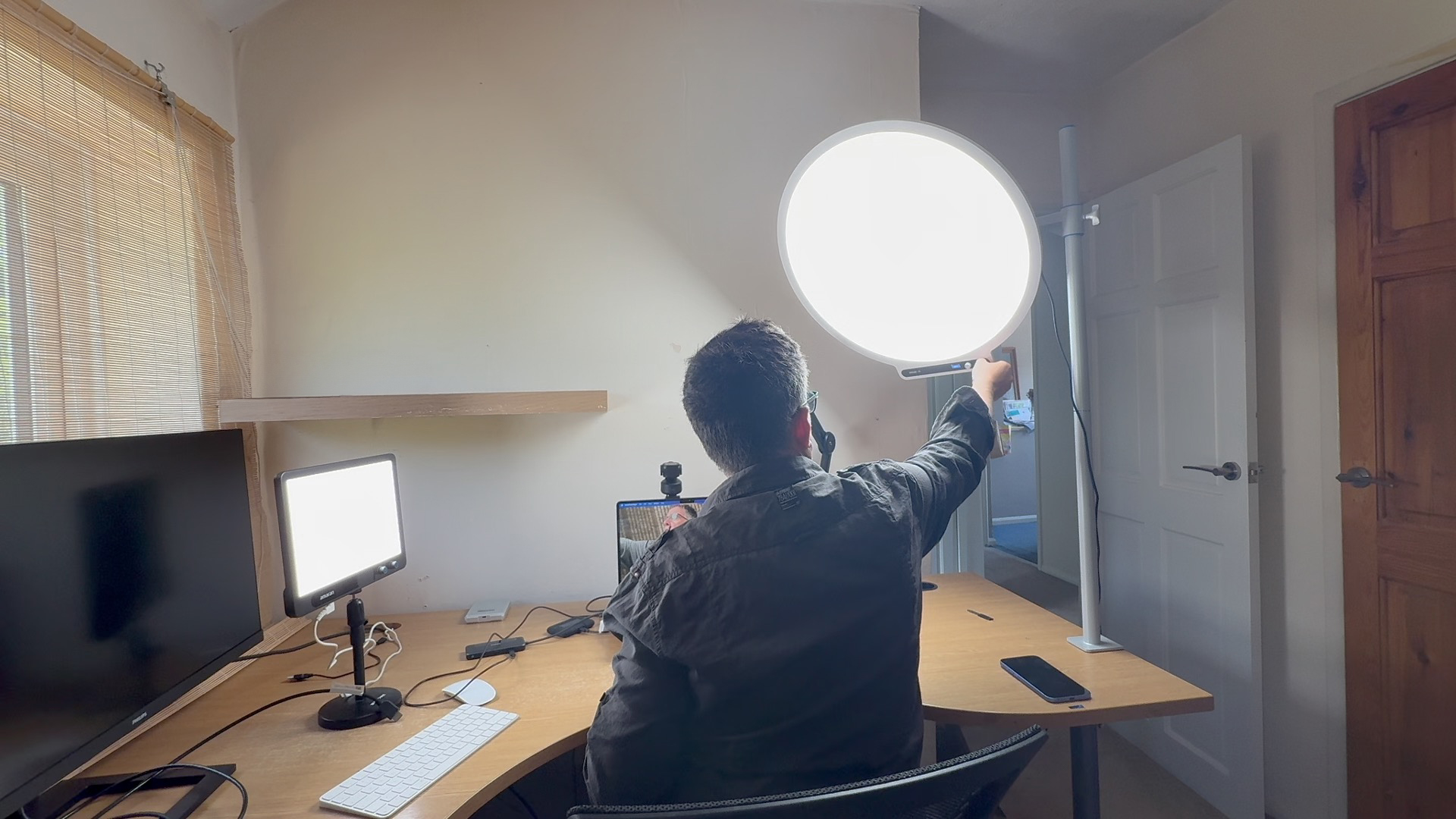Shot of a home office where a vlogger adjusts the position of the large circular Amaran Verge Max